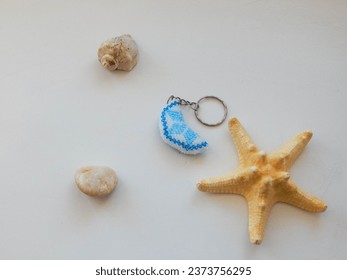 Colored key chain and sea conch. Bead colorful key chain on a white background