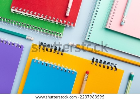 colored notebooks, colored pencils on a light table. Place for your text. High quality photo