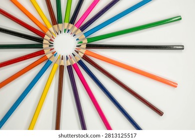 colored pencils are arranged in a circular pattern on a white surface