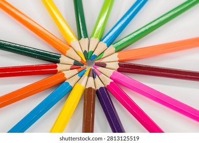colored pencils are arranged in a circular pattern on a white surface
