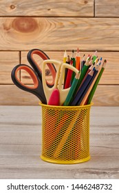 Colored pencils in basket. School or office supplies on wooden background.