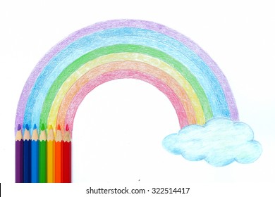 Colored pencils with hand drawing of rainbow and cloud