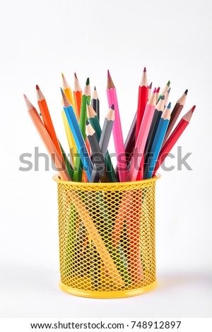 Colored pencils in metal holder. Multicolored pencils in yellow shaped metal basket isolated on white background.