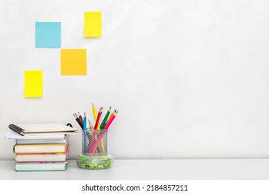 Colored pencils in pencil box with books on the desk near wall. Copy space. - Powered by Shutterstock