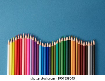 Colored pencils, seamless horizontal pattern colored pencils arranged in a wave with copy space for note, text, on blue background. 