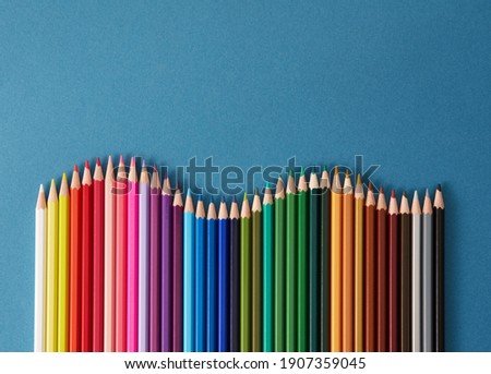 Colored pencils, seamless horizontal pattern colored pencils arranged in a wave with copy space for note, text, on blue background. 