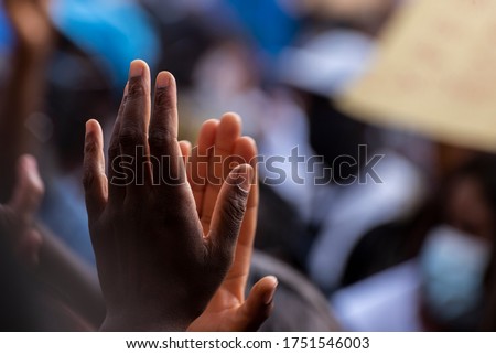 Colored person hands clapping in the middle of a protest against racism, unfocused background