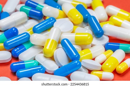 Colored pills, pills and capsules on a red background - Shutterstock ID 2254436815