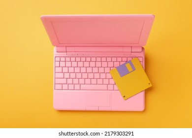 Colored PinColored Pink Laptop With Bright Floppy Disk, Modernity Concept.k Laptop With Bright Floppy Disk, Modernity Concept. High Quality Photo