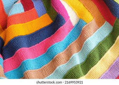 Colored plaid from different yarns. Knitted texture, woolen product, homework, hobbies, knitting, needlework. Close-up, background.