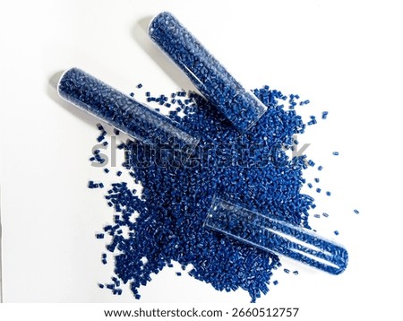 Colored plastic granules, blue masterbatch with glass tube carrying pigment, polymer dispersed in white background, isolated with glass tube, suitable for industrial plastic product catalog design