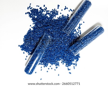 Colored plastic granules, blue masterbatch with glass tube carrying pigment, polymer dispersed in white background, isolated with glass tube, suitable for industrial plastic product catalog design