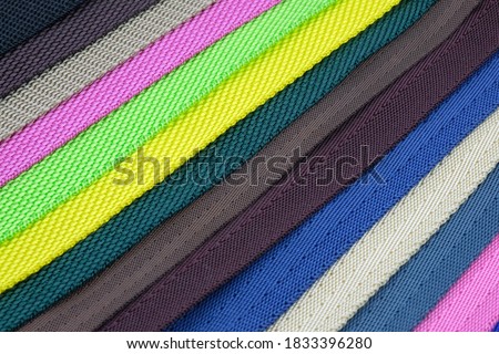 Colored polyester belts, sample palette for making shoulder straps for bags and backpacks. Belt straps for bags, and for sewing dog collars. Colored background from belts folded diagonally.