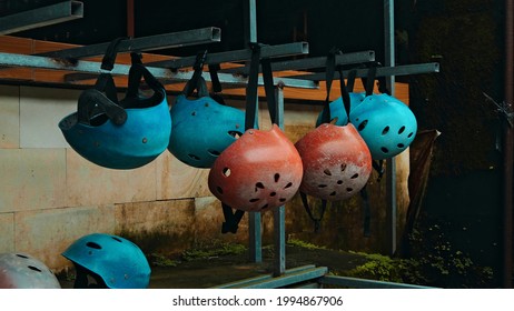 Colored protective helmets for the head to practice rafting hanging on the wall on the street