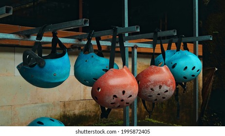 Colored protective helmets for the head to practice rafting hanging on the wall on the street
