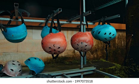 Colored protective helmets for the head to practice rafting hanging on the wall on the street