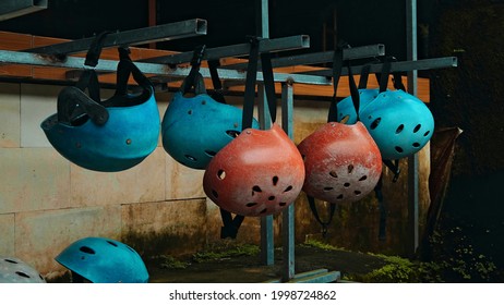 Colored protective helmets for the head to practice rafting hanging on the wall on the street