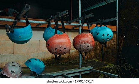 Colored protective helmets for the head to practice rafting hanging on the wall on the street