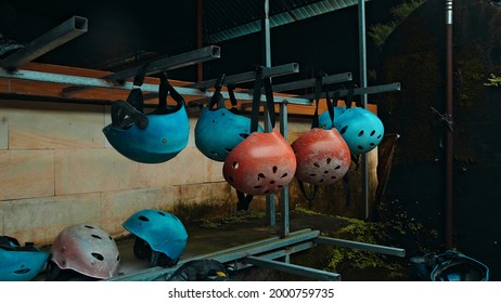 Colored protective helmets for the head to practice rafting hanging on the wall on the street