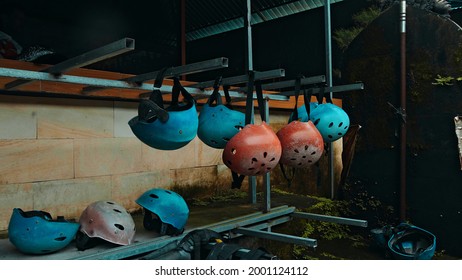 Colored protective helmets for the head to practice rafting hanging on the wall on the street