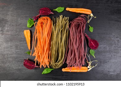 Colored Raw Vegetable Vegetarian Pasta with Beets, Carrots and Spinach. Flat lay. Copy space. Top view. Frame. - Powered by Shutterstock