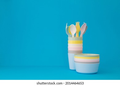 Colored reusable plates glasses spoons and forks on blue background copy space. Tableware for serving in pastel colors for a children's party - Shutterstock ID 2014464653
