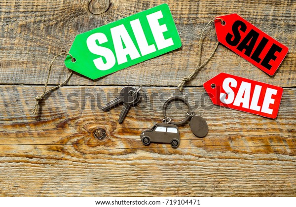 Colored sale labels and car keys on wooden\
background top view\
copyspace
