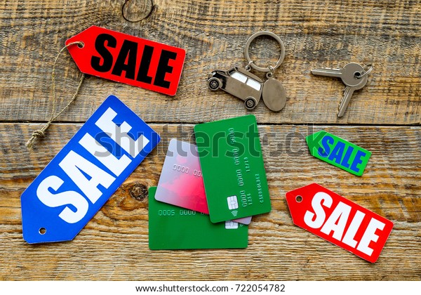 Colored sale labels, car keys and bank cards on\
wooden background top view\
copyspace