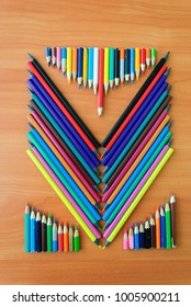 Colored sharp pencils for children's creativity on a wooden background, in places poked