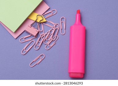Colored sticky notes and paper clips and pink marker on purple background
