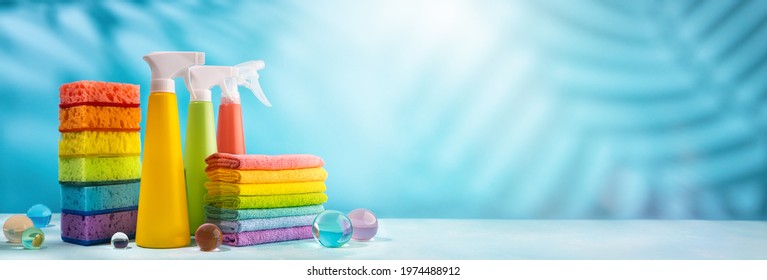 Colored supplies for cleaning on blue background.Spray Bottles of detergent, sponges and rags rainbow colors. Concept of spring cleaning home.