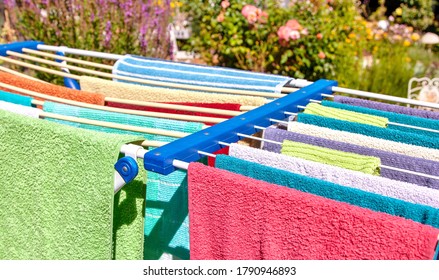 Colored Towels To Be Dried On A Clothes Horse Outside. Fresh Clean Towels Drying On Washing Line Outdoor. Laundry Hangs On The Dryer. Drying Clean Clothes After Washing, Homework Concept