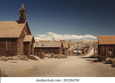 Colored vintage old looking photo of empty streets of abandoned ghost town Bodie in California, USA in the middle of a day.