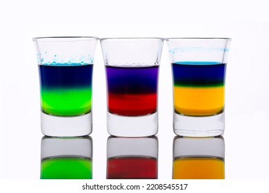 Colored Water Layers In Shot Glasses Isolated On White Background