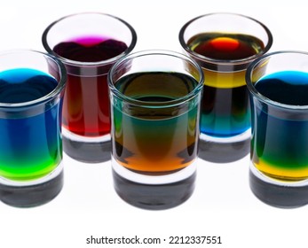 Colored Water Layers In Shot Glasses Isolated On White Background