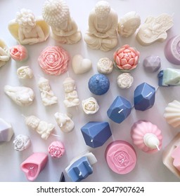 lot of colored and white candles made of soy wax of different figures, angels, flowers, buddha, crystals