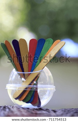 colored wood pieces in plastic cup on wood ground and white bokeh on green background 
