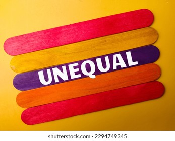 Colored wooden stick with the word UNEQUAL on yellow background