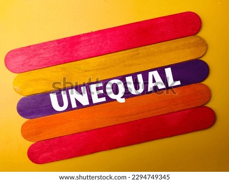 Colored wooden stick with the word UNEQUAL on yellow background