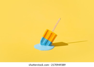 Colored yellow and blue ice cream melts from the hot sun. Hot weather concept