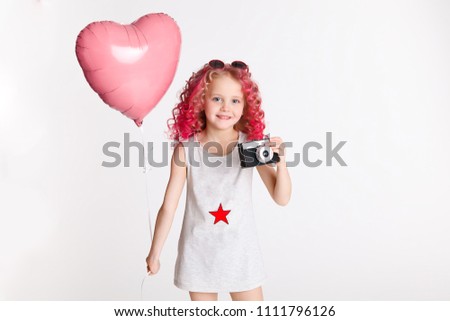 Colores hairs. Portrait of funny fashion hipster girl with pink ballon in the shape of heart. Retro camera in her hand.