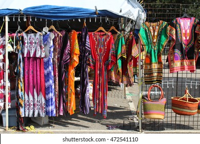 Colorful African dashikis, dresses and woven bags at an outdoor flea market