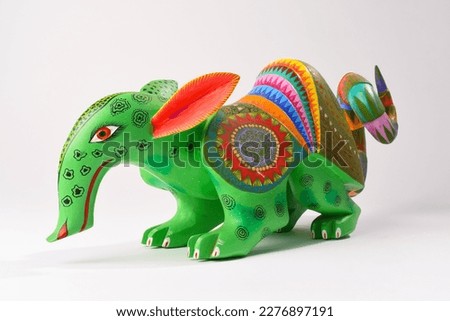Colorful alebrije. Mexican hand painted wooden craft in the shape of a combination of armadillo and anteater on a white background. Oaxaca, Mexico.
