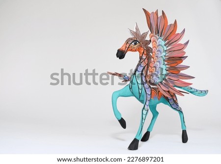 Colorful alebrije. Mexican hand painted wooden handicraft in the shape of a horse with wings on white background. Oaxaca, Mexico. Copy space