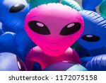 Colorful alien blowup dolls with large black eyes on sale in a carnival stand.