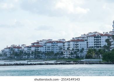 Colorful apartment buildings with balconies line the vibrant waterfront in Miami, Florida. This scene evokes a relaxed vacation atmosphere, inviting you to unwind and soak up the ocean views. - Powered by Shutterstock