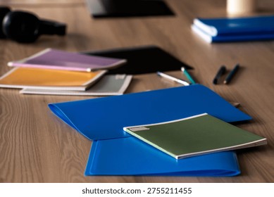 A Colorful Array of Notebooks and Pens Spread Across a Wooden Table in a Creative Workspace Environment