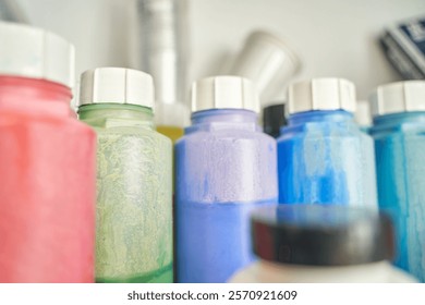 Colorful array of plastic paint bottles in a row on shelf closeup with focus on shapes and textures.