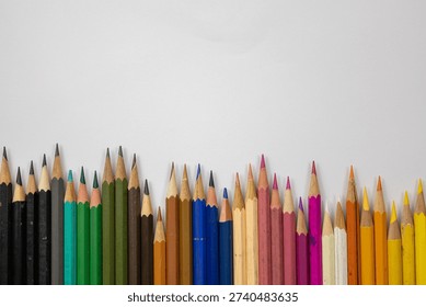 Colorful array of sharpened pencils forming a vibrant bottom border on a white background