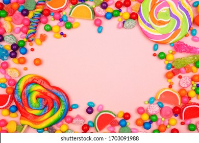 Colorful assortment of candies. Top view frame over a pink background. - Shutterstock ID 1703091988